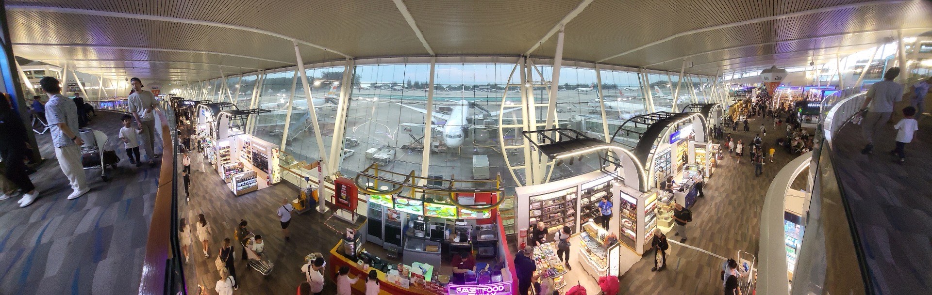 The airside departures area of the International Terminal — shops and gates overlooking the apron at HKT